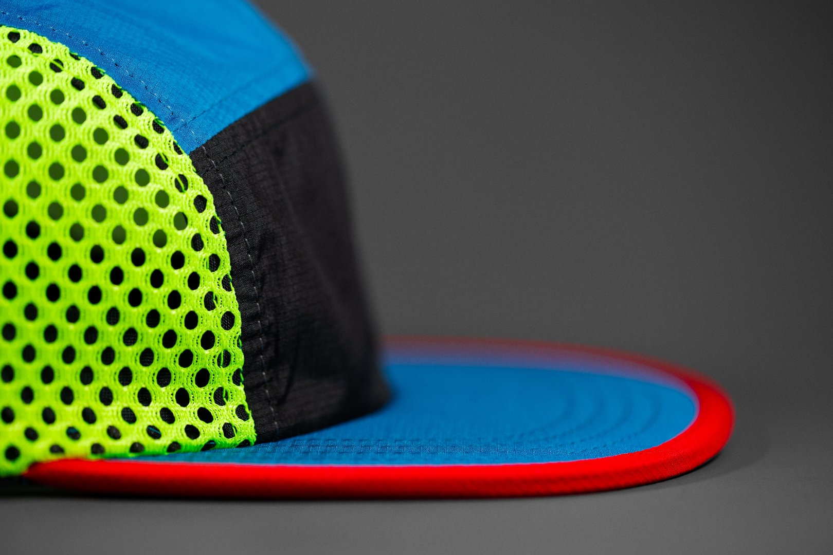 The Ultra 5 Panel Performance Trucker Hat by Blvnk Headwear front profile shot with neon green mesh, black micro ripstop front panel, emerald bill and top panels, finished off with a laser red binding on the bill.