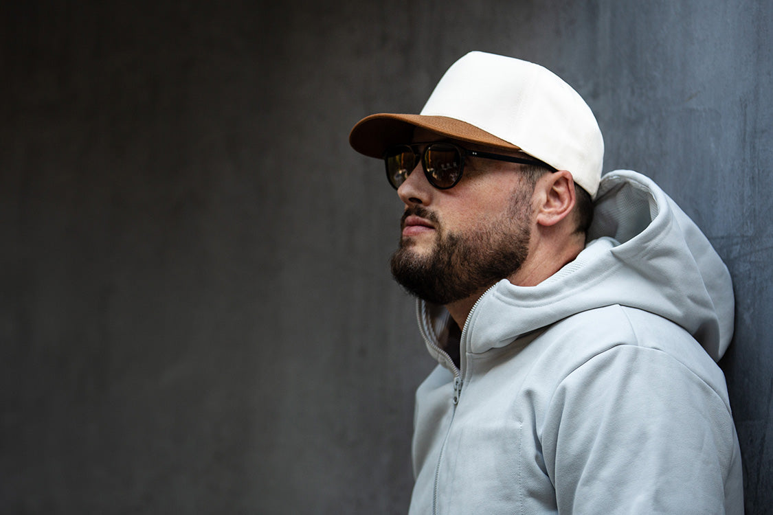 all-groups Blvnk Headwear Vision Vintage Shape Snapback Hat NATURAL BROWN SUEDE on man in hoodie agains a concrete wall.