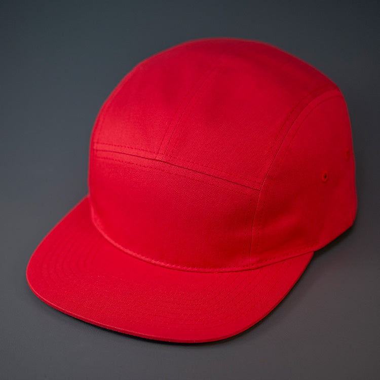A Red, Cotton Twill, Blank 5 Panel Camp Hat With a Flat Bill, & Woven Nylon Strapback. Designed by Blvnk Headwear.