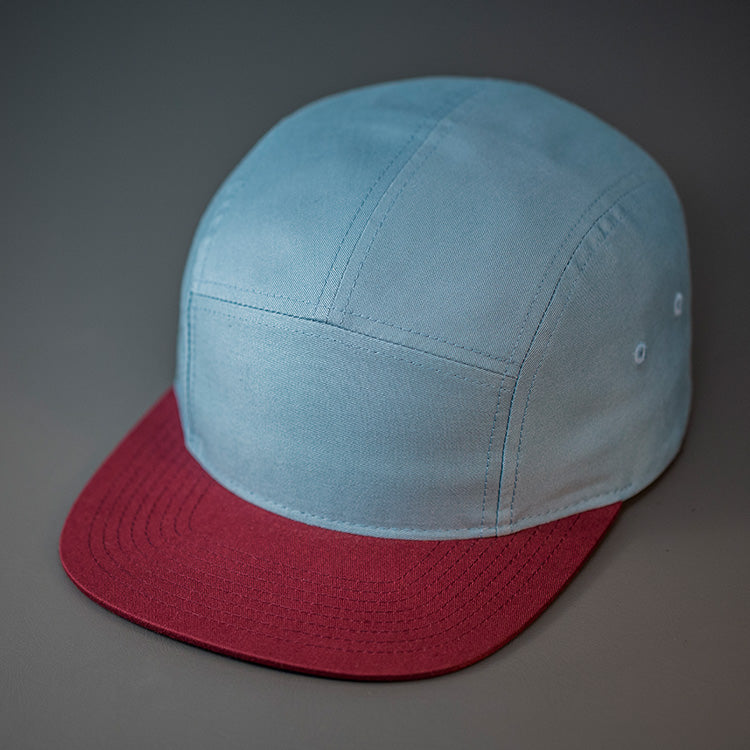 A Smoke Blue & Maroon, Cotton Twill, Blank 5 Panel Camp Hat With a Flat Bill, & Woven Nylon Strapback. Designed by Blvnk Headwear.