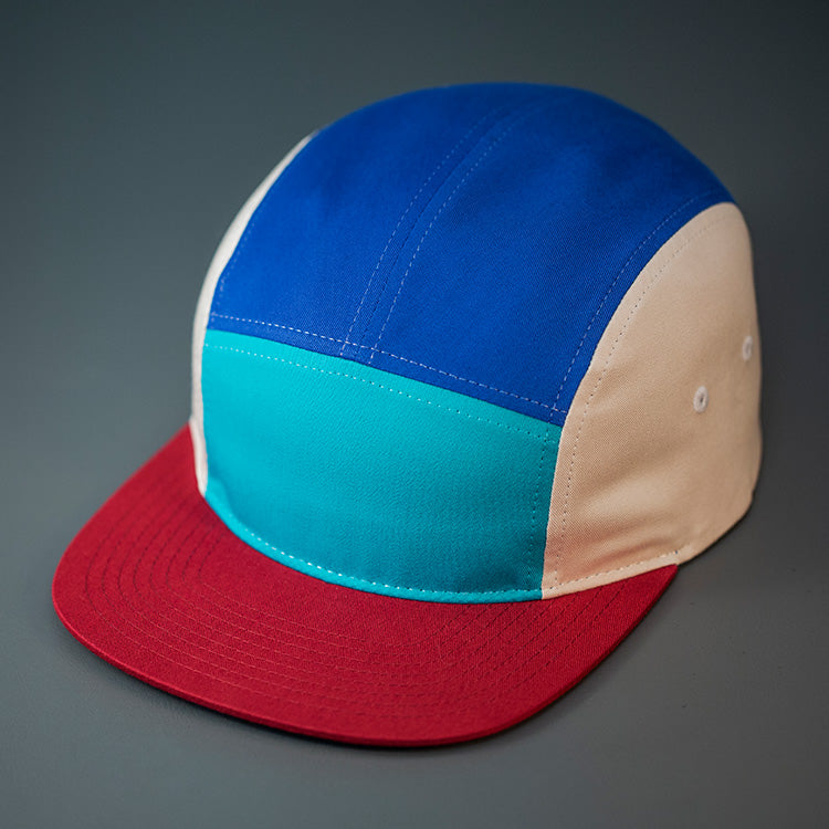 A Teal front, Blue Ribbon top, Birch sided, Cotton Twill, Blank 5 Panel Camp Hat With a Flat, Dark Cardinal Bill, & Woven Nylon Strapback. Designed by Blvnk Headwear.