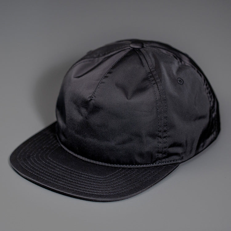 A Black, Unstructured Satin Nylon, Blank Hat W/ a Pinch Front Crown, Flat Bill & a Classic Snapback. | Designed by Blvnk Headwear