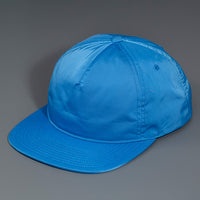A Blue, Unstructured Satin Nylon, Blank Hat W/ a Pinch Front Crown, Flat Bill & a Classic Snapback.  |  Designed by Blvnk Headwear