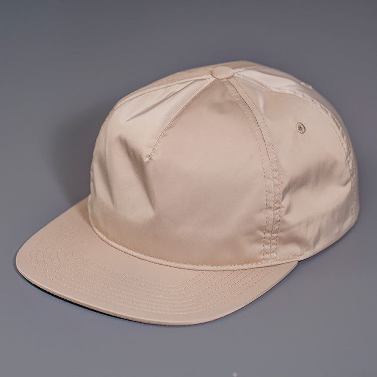A Champagne colored, Unstructured Satin Nylon, Blank Hat W/ a Pinch Front Crown, Flat Bill & a Classic Snapback. | Designed by Blvnk Headwear