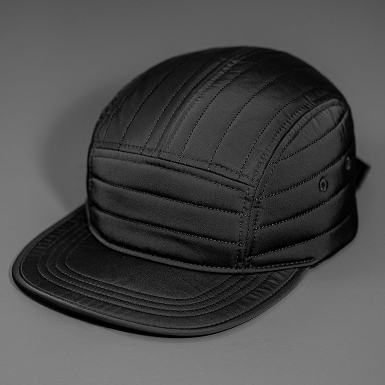 A Black Quilted Nylon, Blank 5 Panel Camp Hat featuring a Packable Visor, Satin Lining & a Woven Nylon Backstrap. | Designed by Blvnk Headwear
