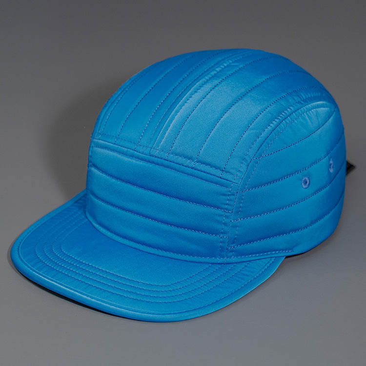 An Old Blue Quilted Nylon, Blank 5 Panel Camp Hat featuring a Packable Visor, Satin Lining & a Woven Nylon Backstrap. | Designed by Blvnk Headwear