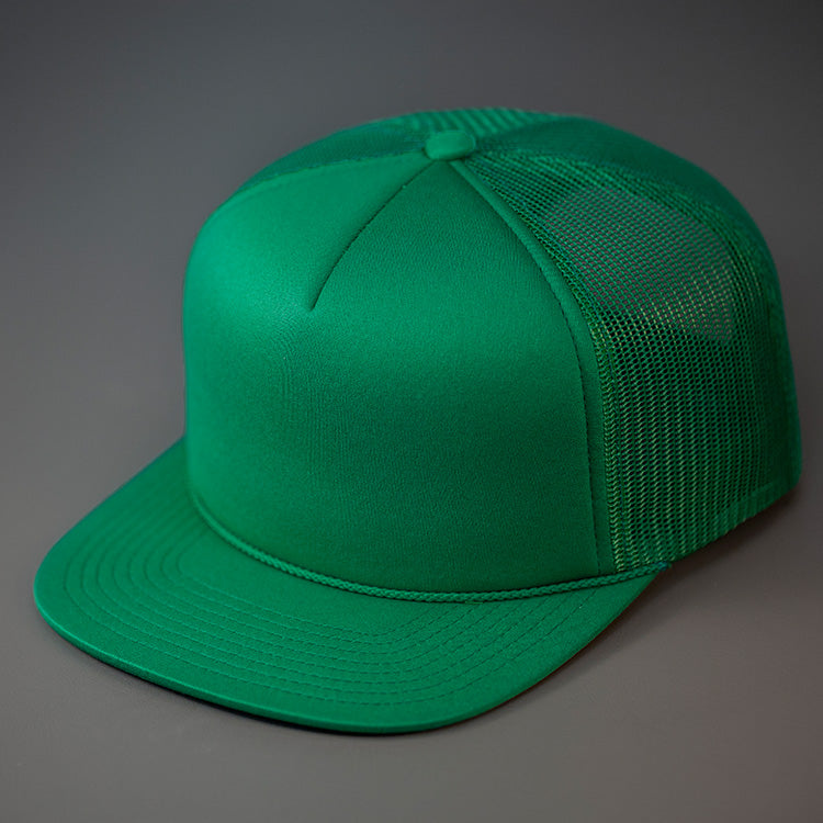 A Green, Foam Front, Mesh Backed Blank Trucker Hat with a Flat Bill, & Classic Snapback. Designed by Blvnk Headwear.