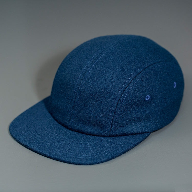 A Navy, Melton Wool, Blank 4 Panel Hat with a Flat Bill, & Vegan Leather Strapback. Designed by Blvnk Headwear.