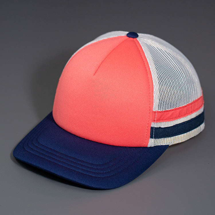 A Coral Low Profile Foam Front, Coral & Navy Striped, Birch Mesh Back, Blank Trucker Hat with a Navy Blue Curved Bill, & Classic Snapback. Designed by Blvnk Headwear.