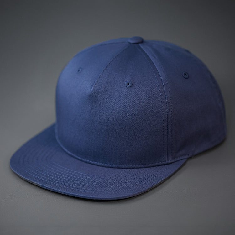 A Navy Colored, Cotton Twill, Pinch Front, Blank Snapback Hat. Designed & Manufactured by Blvnk Headwear.