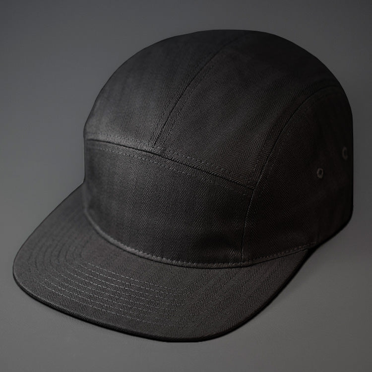 A Black, Herringbone, Blank 5 Panel Camp Hat With a Flat Bill. Designed by Blvnk Headwear.