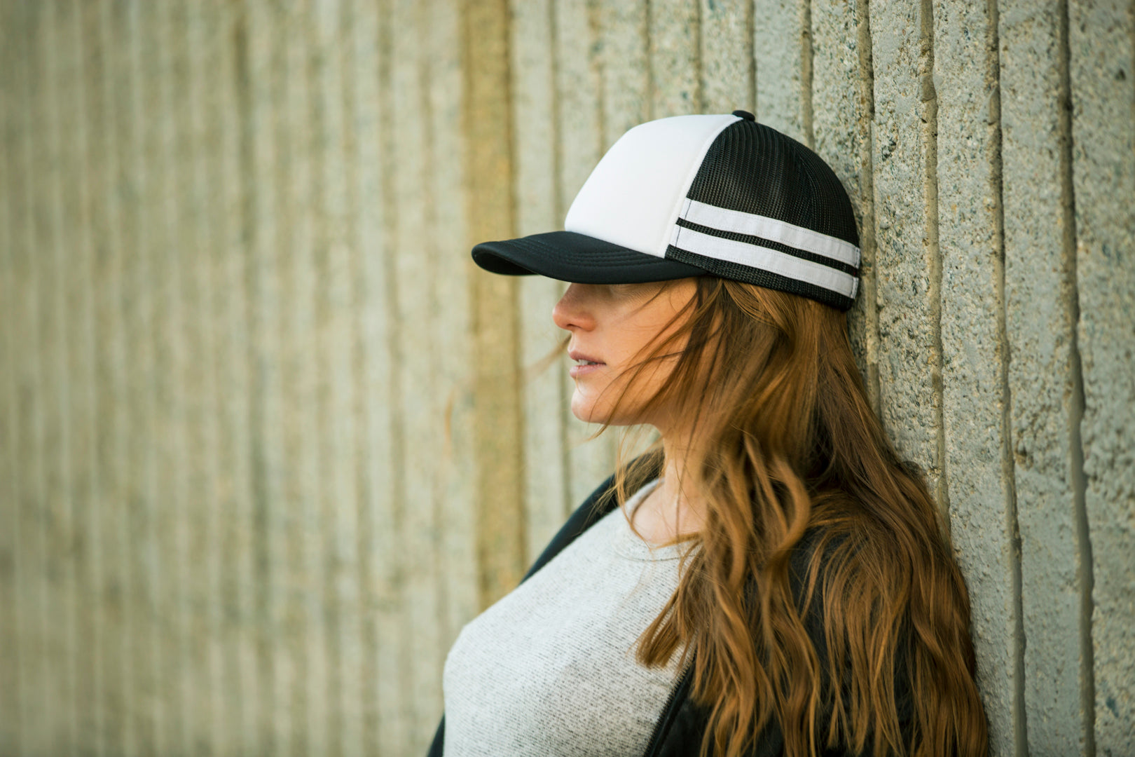 Girl wearing Blvnk Headwear's Lowtide blank striped trucker hat against a wall at Chrissy Field in San Francisco, CA.