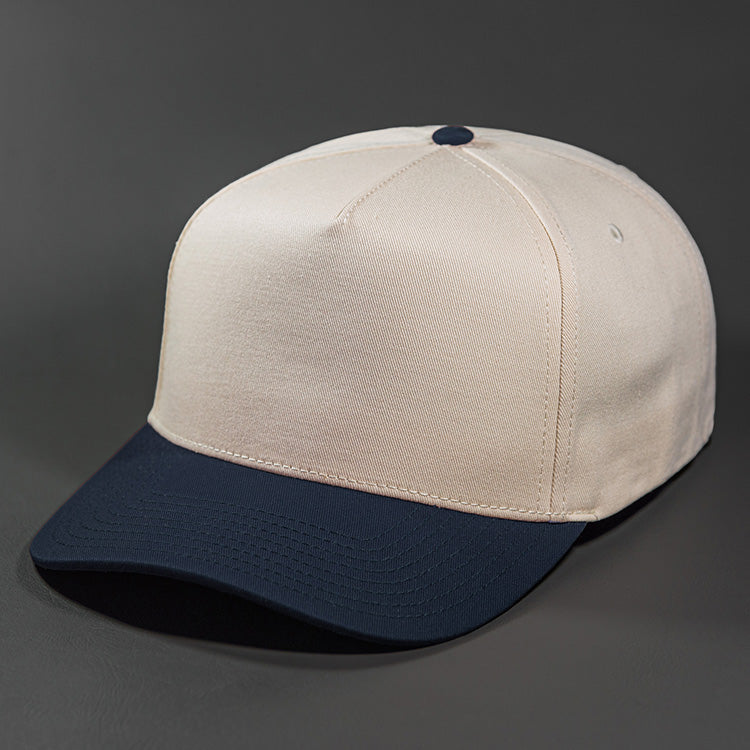 The Blvnk Headwear Origin Vintage Shape Blank Snapback Hat in the Natural and Navy color way.