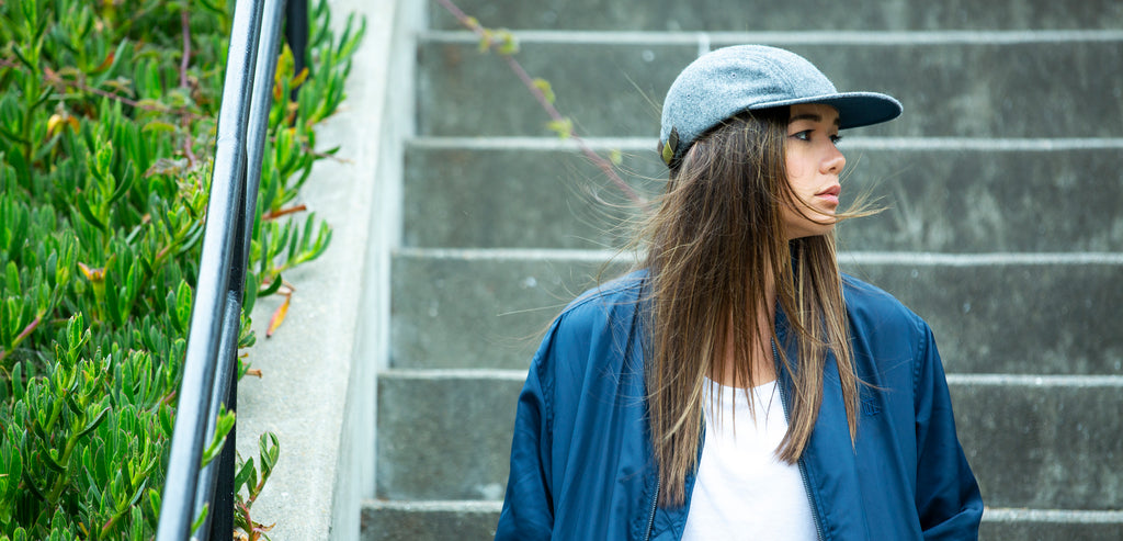 Blvnk Forest flat bill 4 panel blank strap back hat in heather grey on girl near stairs.