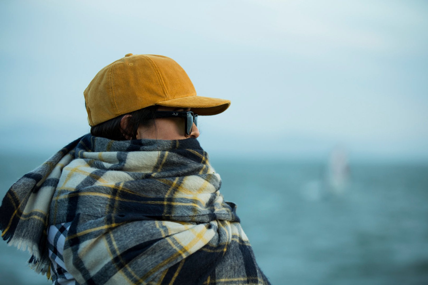 Girl wearing BLVNK HEADWEAR's blank corduroy Step Dad hat with a plaid shawl near the ocean.