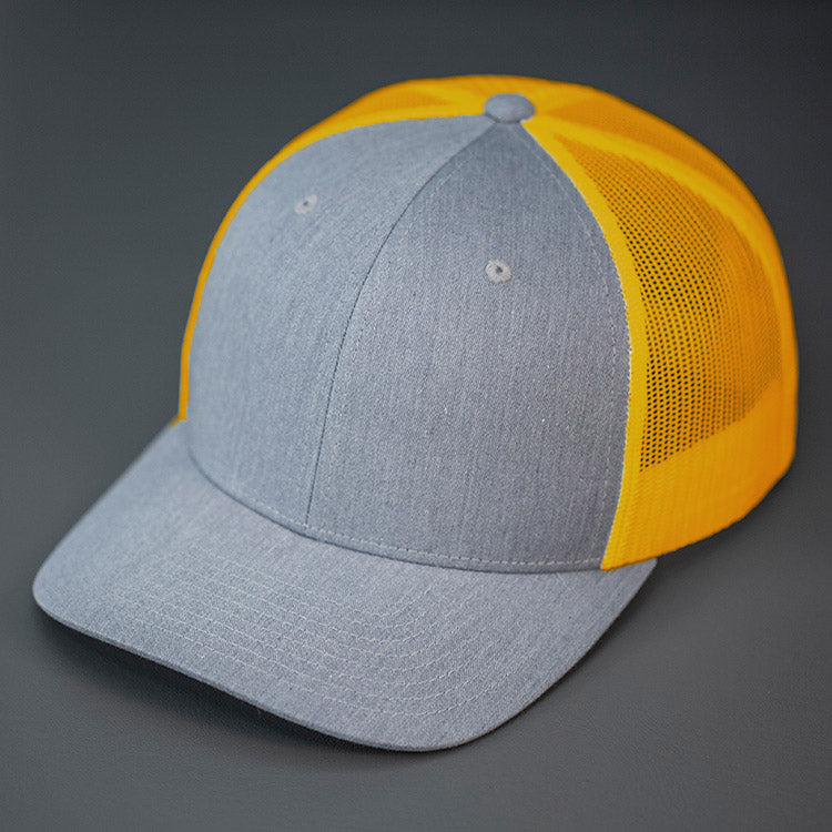 A Heather Grey & Amber Gold, Cotton Twill, Mesh Backed, Blank Trucker Hat with a Pre Curved Bill, & Classic Snapback. | Designed by Blvnk Headwear