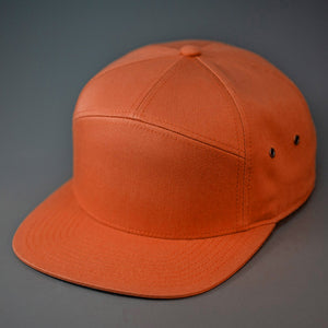 A Dark Orange colored, Cotton Twill, Blank 7 Panel Hat with a Flat Bill, Brass Details, & Vegan Leather Strapback. Designed by Blvnk Headwear