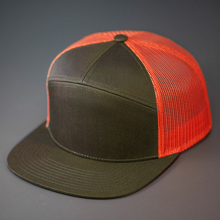 A Dark Loden & Nasturtium, Cotton Twill, Mesh Backed Blank 7 Panel Trucker Hat with a Flat Bill, & Classic Snapback. Designed by Blvnk Headwear