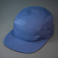 A Light Navy, Cotton Twill, Blank 5 Panel Camp Hat With a Flat Bill, & Woven Nylon Strapback.  Designed by Blvnk Headwear.