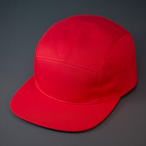 A Red, Cotton Twill, Blank 5 Panel Camp Hat With a Flat Bill, & Woven Nylon Strapback.  Designed by Blvnk Headwear.