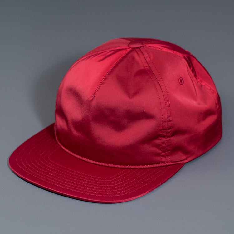 A Maroon Colored, Unstructured Satin Nylon, Blank Hat W/ a Pinch Front Crown, Flat Bill & a Classic Snapback.  |  Designed by Blvnk Headwear