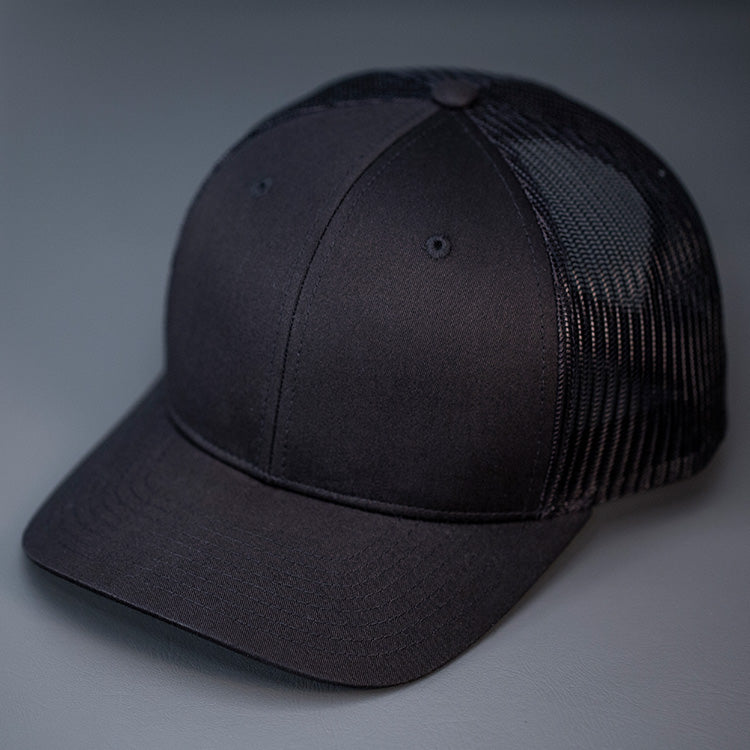 A Black, Cotton Twill, Mesh Backed, Blank Trucker Hat with a Pre Curved Bill, & Classic Snapback.  |  Designed by Blvnk Headwear