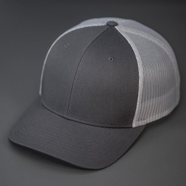 A Charcoal & Grey, Cotton Twill, Mesh Backed, Blank Trucker Hat with a Pre Curved Bill, & Classic Snapback.  |  Designed by Blvnk Headwear