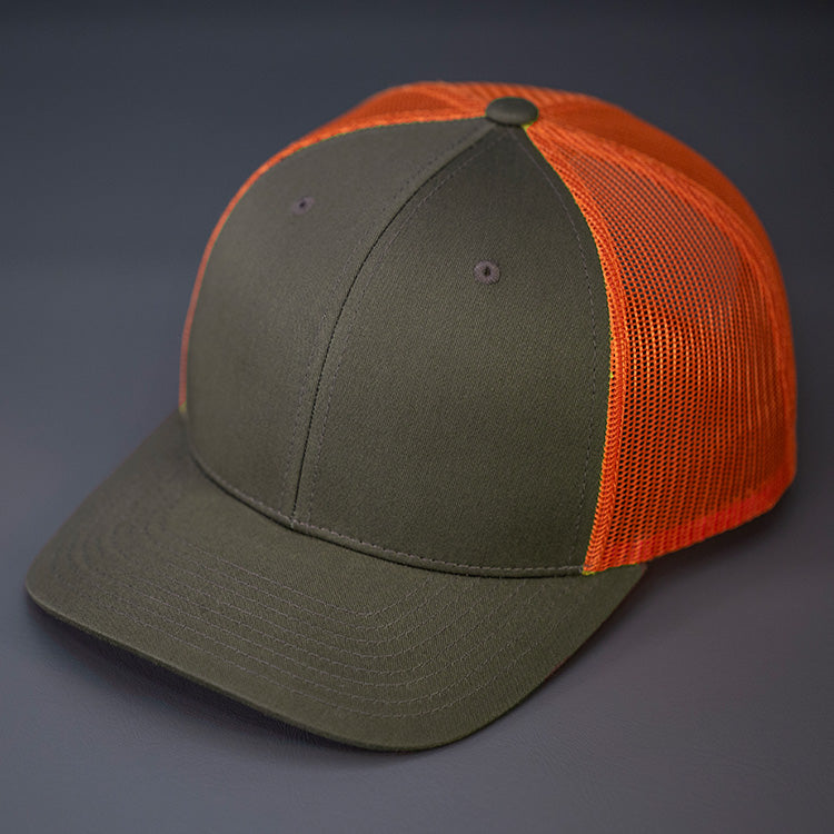 A Dark Loden & Jaffa Orange, Cotton Twill, Mesh Backed, Blank Trucker Hat with a Pre Curved Bill, & Classic Snapback.  |  Designed by Blvnk Headwear