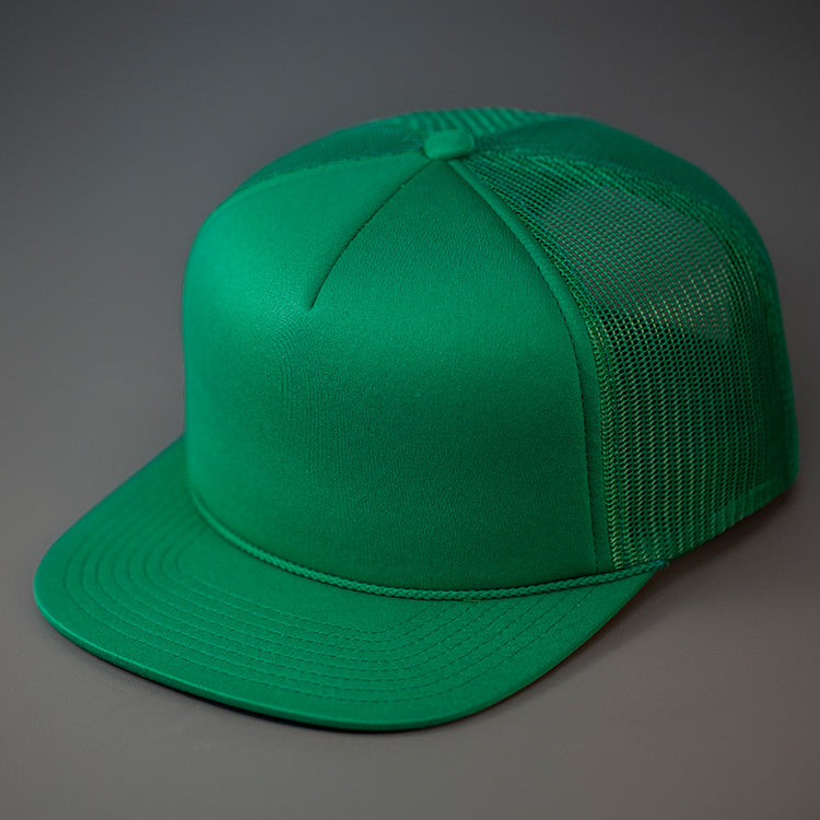 A Green, Foam Front, Mesh Backed Blank Trucker Hat with a Flat Bill, & Classic Snapback.  Designed by Blvnk Headwear.