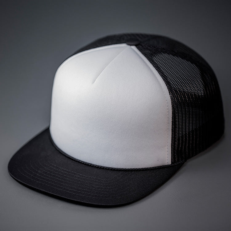 A White & Black, Foam Front, Mesh Backed Blank Trucker Hat with a Flat Bill, & Classic Snapback.  Designed by Blvnk Headwear.