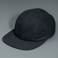 A Black, Melton Wool, Blank 4 Panel Hat with a Flat Bill, & Vegan Leather Strapback.  Designed by Blvnk Headwear.