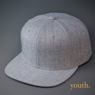 A Youth Sized, Heather Grey, Wool, 6 Panel, Flat Bill, Blank Snapback.  Designed by Blvnk Headwear.