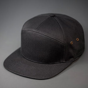 A Black, Cotton Twill, Blank 7 Panel Hat with a Flat Bill, Brass Details, & Vegan Leather Strapback.  Designed by Blvnk Headwear