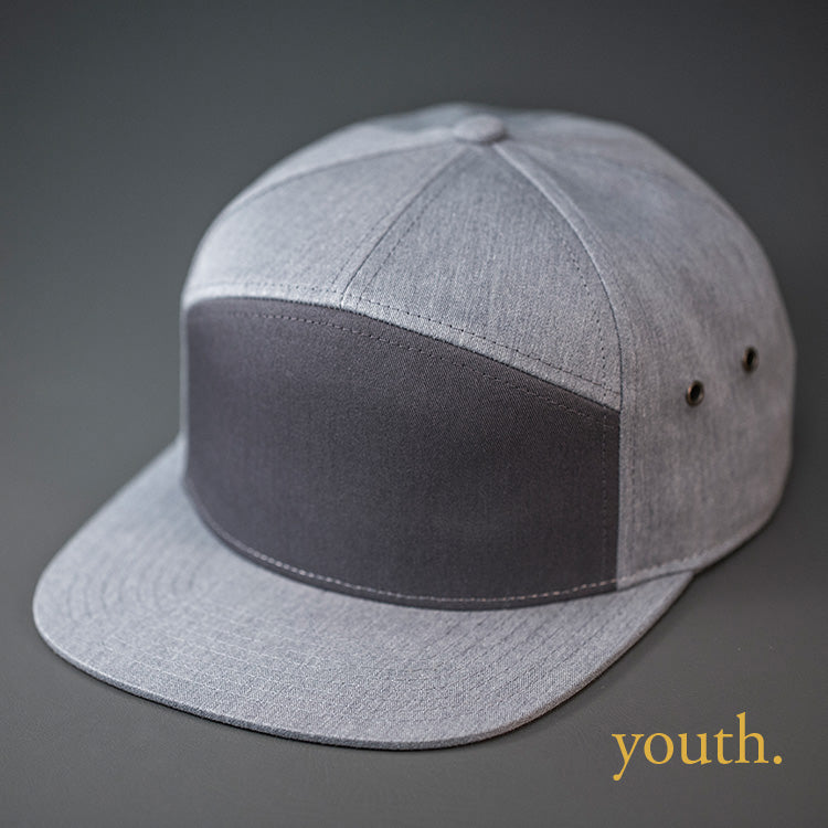 A Youth Sized, Charcoal & Heather Grey, Cotton Twill, Blank 7 Panel Hat with a Flat Bill, Brass Details, & Vegan Leather Strapback.  Designed by Blvnk Headwear