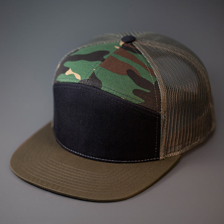 A Black, Camo & Loden Colored, Cotton Twill, Mesh Backed Blank 7 Panel Trucker Hat with a Flat Bill, & Classic Snapback.  Designed by Blvnk Headwear