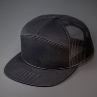 A Black, Cotton Twill, Mesh Backed Blank 7 Panel Trucker Hat with a Flat Bill, & Classic Snapback.  Designed by Blvnk Headwear