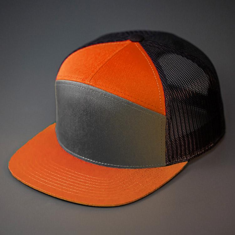A Charcoal, Black & Burnt Orange, Cotton Twill, Mesh Backed Blank 7 Panel Trucker Hat with a Flat Bill, & Classic Snapback.  Designed by Blvnk Headwear