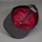 A Maroon Cotton Lining of the Black Chambray, Blank 1 Panel Hat, W/ a Flat Bill & Woven Nylon Strapback.  Designed by Blvnk Headwear.