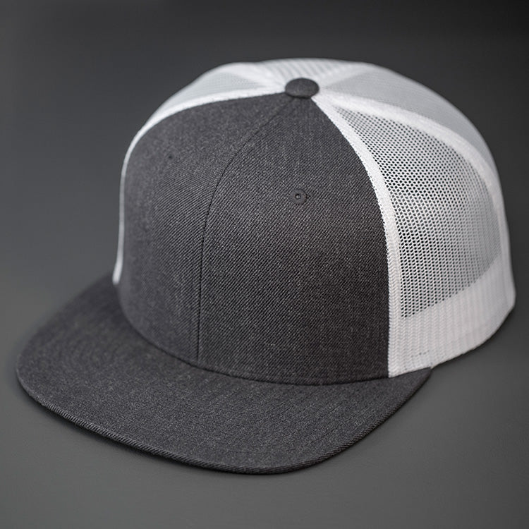 A Heather Charcoal Wool Crown, Blank Trucker Hat, With White Mesh Back Panels, Flat Bill & Classic Snapback.  Designed by Blvnk Headwear.