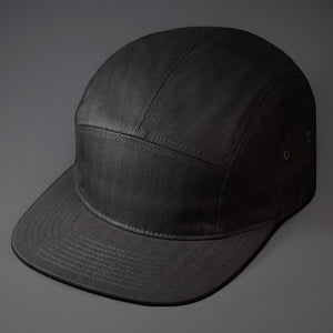 A Black, Herringbone, Blank 5 Panel Camp Hat With a Flat Bill.  Designed by Blvnk Headwear.