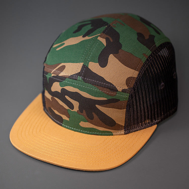 A Camo & Biscuit colored, Cotton Twill/Mesh, Blank 5 Panel Camp Trucker Hat With a Flat Bill, & Woven Nylon Strapback.  Designed by Blvnk Headwear.